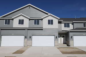 Multi unit property featuring board and batten siding, concrete driveway, stone siding, and a garage