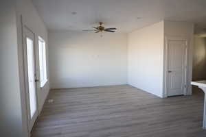 Spare room with wood finished floors, a ceiling fan, and baseboards