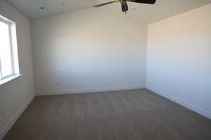 Carpeted spare room featuring lofted ceiling, visible vents, ceiling fan, and baseboards