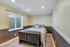 Bedroom with carpet floors, recessed lighting, visible vents, ornamental molding, and wainscoting