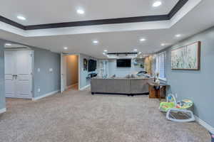 Carpeted living area featuring baseboards, ornamental molding, arched walkways, and recessed lighting