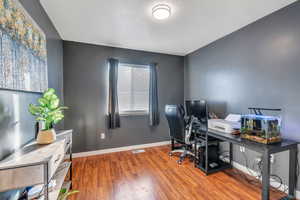 Office area with visible vents, baseboards, and wood finished floors