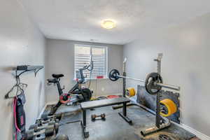 Workout room with baseboards and a textured ceiling