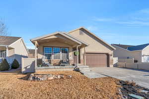 View of front of property featuring concrete driveway, fence, an attached garage, and stucco siding