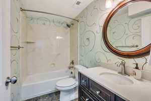 Bathroom with toilet, visible vents,  shower combination, and vanity