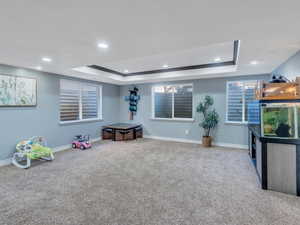 Playroom with a tray ceiling, recessed lighting, carpet flooring, and baseboards