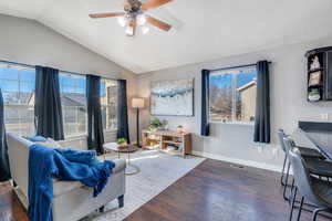 Sitting room with baseboards, visible vents, vaulted ceiling, and wood finished floors