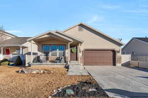 Ranch-style home with a porch, fence, driveway, stone siding, and stucco siding