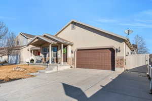 View of front of home with a garage, stone siding, driveway, and stucco siding