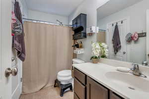 Bathroom with tile patterned floors, vanity, toilet, and a shower with curtain