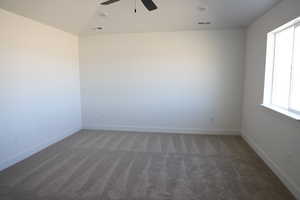 Carpeted spare room featuring a ceiling fan, visible vents, and baseboards