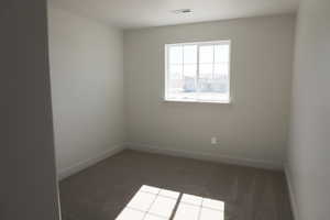 Unfurnished room featuring carpet floors, visible vents, and baseboards