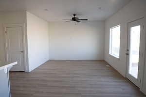 Unfurnished room featuring light wood finished floors, a ceiling fan, and baseboards