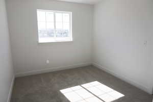 Spare room featuring carpet floors and baseboards