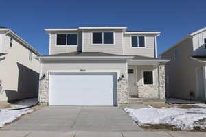 View of front of property featuring a garage, driveway, roof with shingles, and stone siding