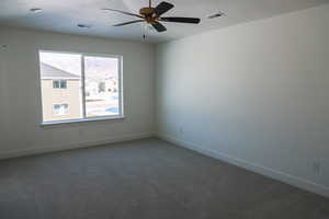 Spare room featuring a ceiling fan, carpet, visible vents, and baseboards