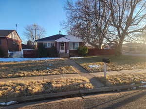 Bungalow featuring brick siding, a front yard, and fence