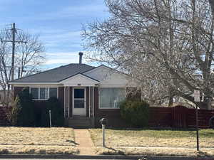 Bungalow with brick siding, a shingled roof, a front yard, and fence