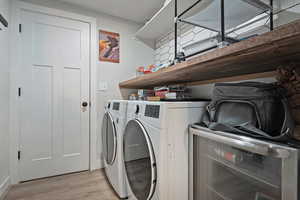 Washroom with light wood-type flooring, laundry area, and separate washer and dryer