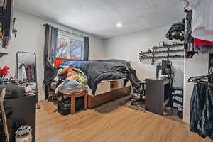 Bedroom with a textured ceiling and wood finished floors