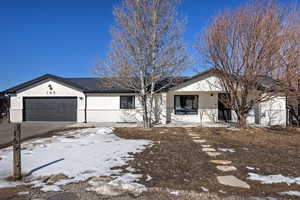 Single story home featuring a garage, covered porch, driveway, and brick siding