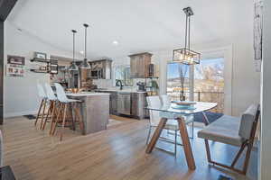 Kitchen with a breakfast bar area, light wood-style flooring, stainless steel appliances, light countertops, and tasteful backsplash