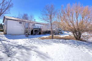 Snow covered house featuring stairs, metal roof, and a deck