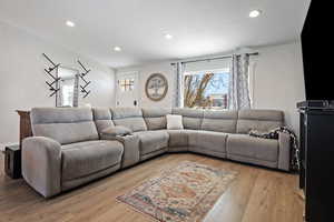 Living area with light wood finished floors and recessed lighting