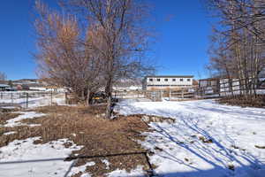 Yard layered in snow featuring fence