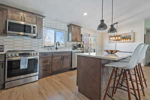 Kitchen featuring stainless steel appliances, light countertops, a sink, and light wood-style flooring