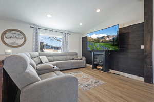 Living room with recessed lighting, wood finished floors, visible vents, baseboards, and vaulted ceiling