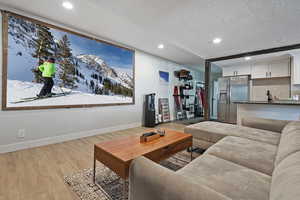 Living area with a textured ceiling, recessed lighting, light wood-style flooring, and baseboards