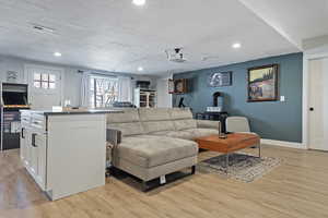 Living area with light wood-style flooring, visible vents, baseboards, and a textured ceiling