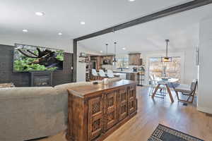 Living area featuring lofted ceiling with beams, recessed lighting, baseboards, light wood finished floors, and a glass covered fireplace