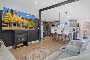 Living room featuring light wood-type flooring, lofted ceiling with beams, baseboards, and recessed lighting