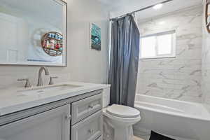 Full bathroom with shower / tub combo with curtain, vanity, and toilet