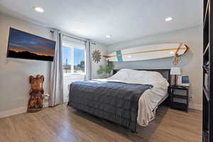 Bedroom featuring a textured ceiling, recessed lighting, wood finished floors, and baseboards