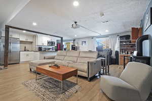 Living area with recessed lighting, visible vents, a textured ceiling, and light wood finished floors