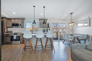 Kitchen featuring stainless steel appliances, light wood finished floors, backsplash, and light countertops