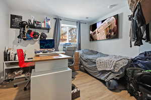 Bedroom with wood finished floors and visible vents