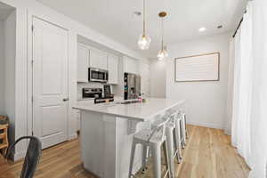 Kitchen with appliances with stainless steel finishes, light countertops, a sink, and light wood finished floors