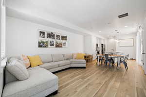 Living room with visible vents, light wood-style flooring, and recessed lighting