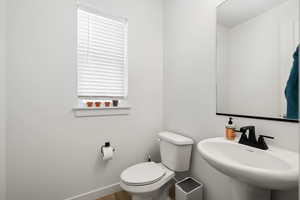 Bathroom featuring a sink, toilet, and baseboards