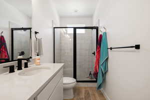 Bathroom featuring wood tiled floor, a shower stall, toilet, and vanity