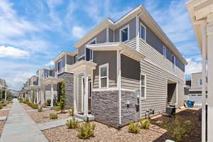 View of property exterior with a residential view, stone siding, and central AC unit