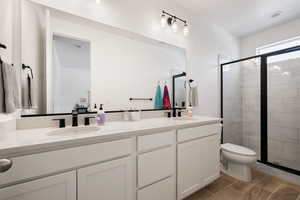 Bathroom featuring toilet, a shower stall, a sink, and wood finish floors