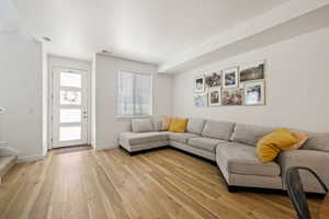 Living room featuring light wood finished floors, stairway, visible vents, and baseboards