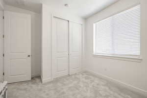 Unfurnished bedroom with baseboards, visible vents, a closet, and light colored carpet