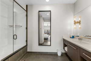 Bathroom featuring baseboards, ensuite bath, tile patterned floors, an enclosed shower, and vanity