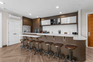 Kitchen with a wall unit AC, a breakfast bar area, a peninsula, stainless steel appliances, and light countertops